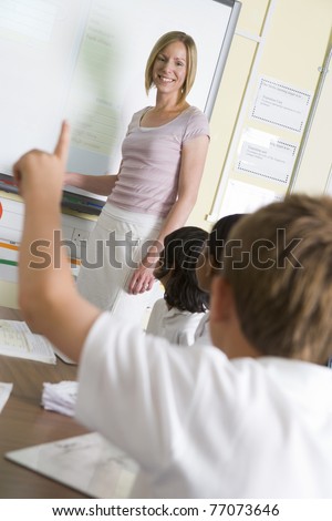 Student volunteering in class with teacher at board
