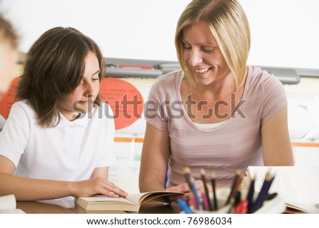 Student in class reading book with teacher