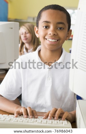 Student at computer terminal typing with student in background (selective focus)