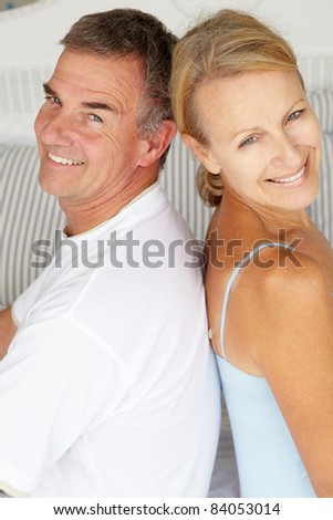 Happy couple sitting back to back on bed