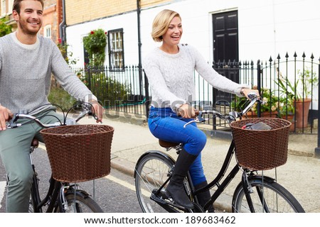 Couple Cycling Along Urban Street Together