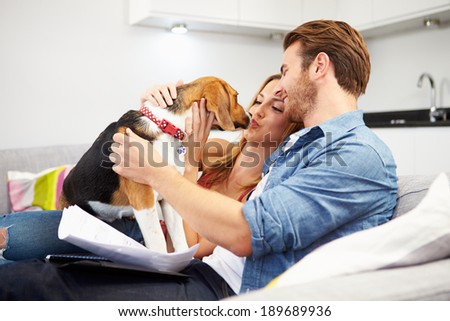 Couple Looking Through Personal Finances At Home With Dog