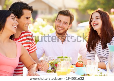 Group Of Friends Enjoying Meal At Outdoor Party In Back Yard