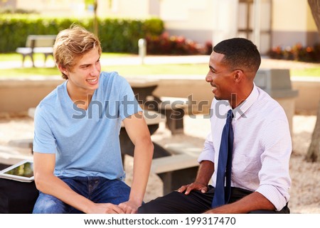 Teacher Sitting Talking To Male High School Student  Outside