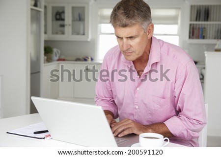 Mid age man working on laptop at home Mid age man working on laptop at home