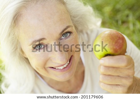 Senior woman eating apple outdoors