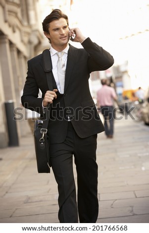 Businessman on phone walking down street