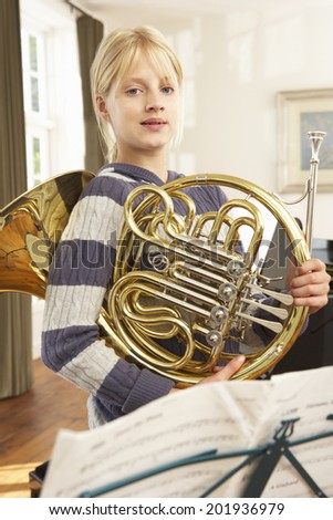 Girl holding French horn at home