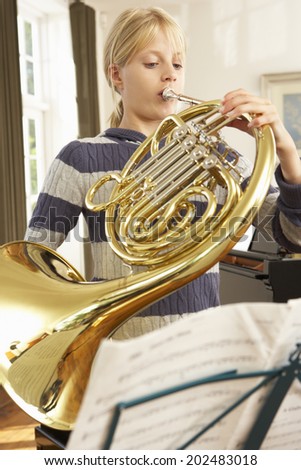 Girl playing French horn at home