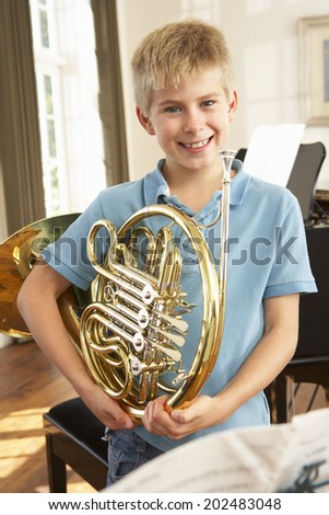 Boy holding French horn at home
