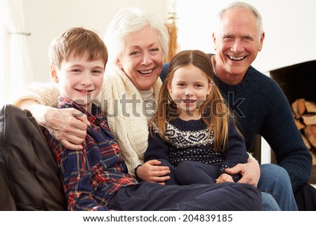 Portrait Of Grandparents Sitting On Sofa With Grandchildren