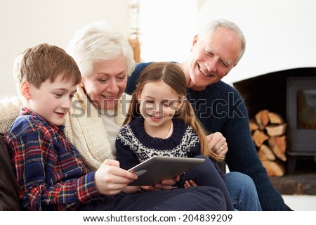 Grandparents Using Digital Tablet On Sofa With Grandchildren