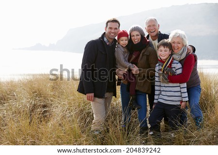 Multi Generation Family In Sand Dunes On Winter Beach