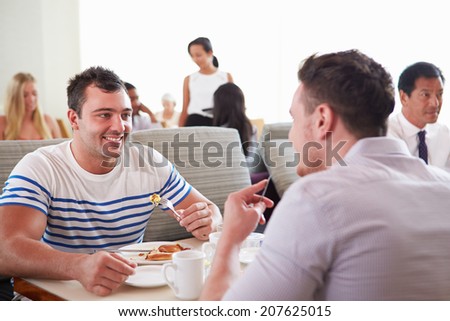 Two Men Enjoying Breakfast In Hotel Restaurant