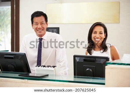 Portrait Of Reception Staff At Hotel Front Desk