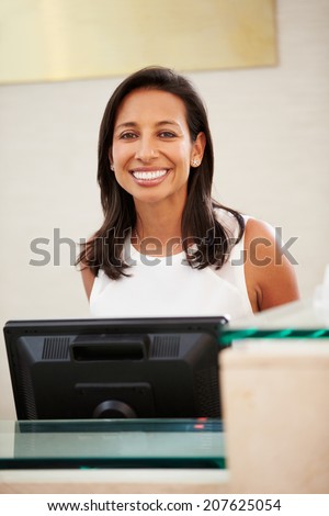 Portrait Of Female Receptionist At Hotel Front Desk