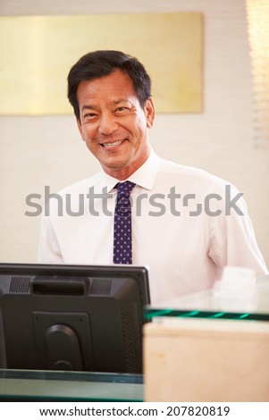Portrait Of Male Receptionist At Hotel Front Desk
