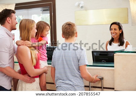 Family Checking In At Hotel Reception