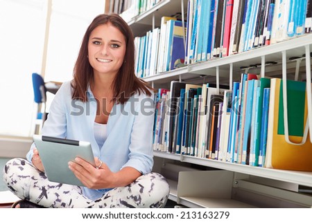 Female College Student Studies In Library On Digital Tablet