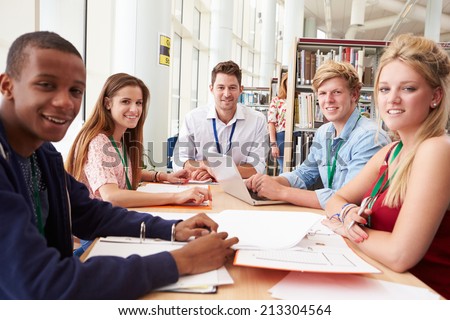 Group Of Students Working Together In Library With Teacher