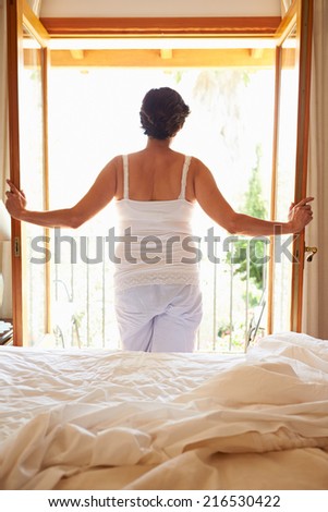 Rear View Of Woman Waking Up In Bed In Morning