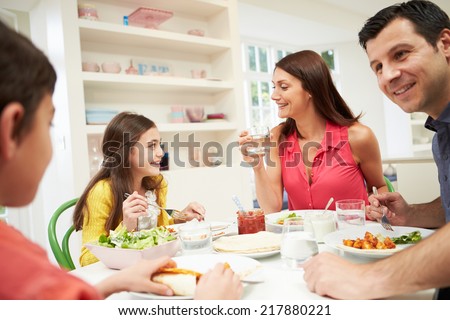 Hispanic Family Sitting At Table Eating Meal Together