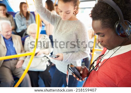 Passengers Using Mobile Devices On Bus Journey