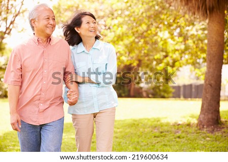 Senior Asian Couple Walking Through Park Together Senior Asian Couple Walking Through Park Together