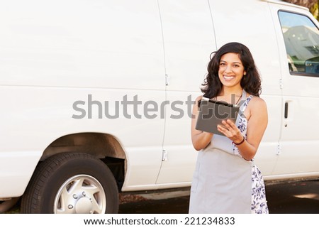 Woman Wearing Apron With Digital Tablet In Front Of Van