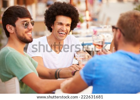 Group Of Male Friends Enjoying Meal In Outdoor Restaurant