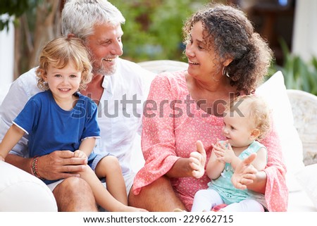 Grandparents At Home Sitting Outdoors With Grandchildren