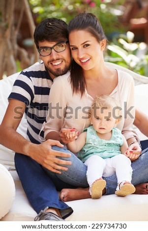 Family Sitting Outdoors In Garden At Home Together