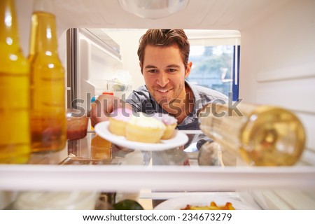 Man Looking Inside Fridge Full Of Unhealthy Food