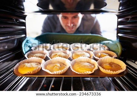 Man Putting Cupcakes Into Oven To Bake