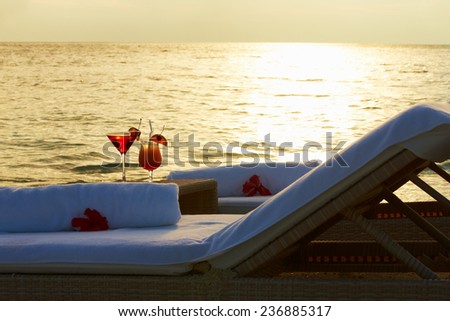 Loungers At Edge Of Tropical Sea With Cocktails