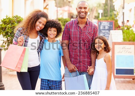 Portrait Of Family Walking Along Street With Shopping Bags