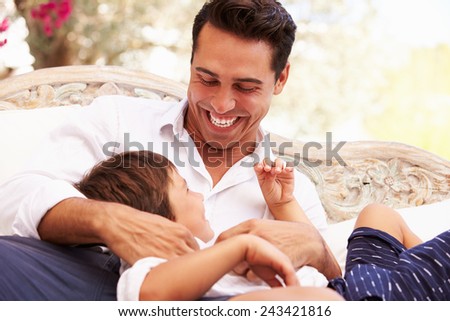 Father At Home Sitting On Outdoor Seat And Playing With Son