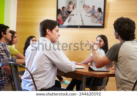 Designers Sitting Around Table In Meeting Looking At Screen
