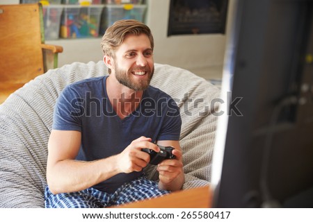 Man Wearing Pajamas Sitting In Chair And Playing Video Game