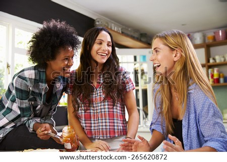 Three Female Friends Making Pizza In Kitchen Together