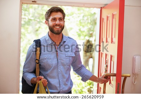 Young Man Returning Home For Work With Shopping