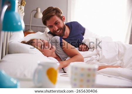 Young Couple relaxing And Laughing In Bed Together