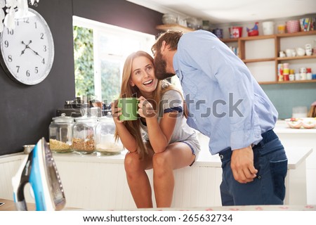 Man Getting Ready To Leave For Work Kisses Woman In Kitchen