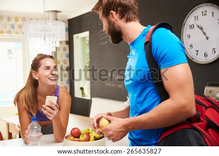 Couple Wearing Gym Clothing Talking In Kitchen