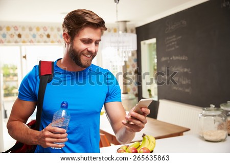 Man Wearing Gym Clothing Looking At Mobile Phone