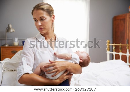 Unhappy Mother Dressed For Work Holding Baby In Bedroom