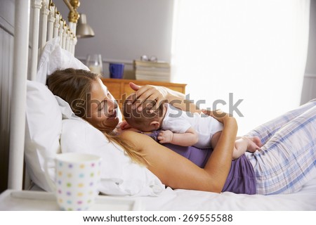 Mother In Bed Holding Sleeping Newborn Baby Daughter