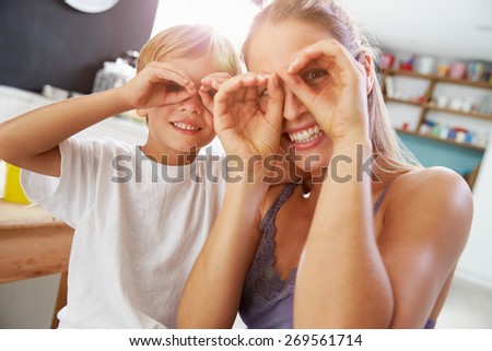 Mother And Son Making Funny Faces At Breakfast Table