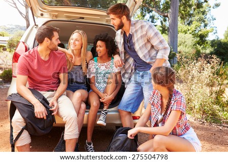 Group Of Friends On Trip Sitting In Trunk Of Car