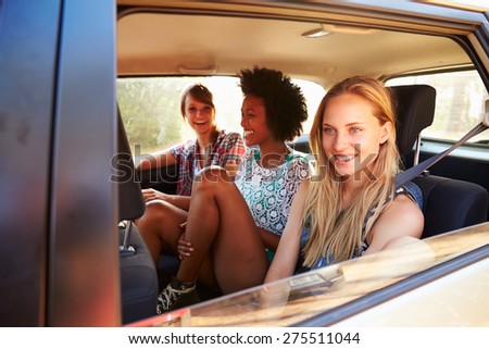 Three Women Sitting In Rear Seat Of Car On Road Trip